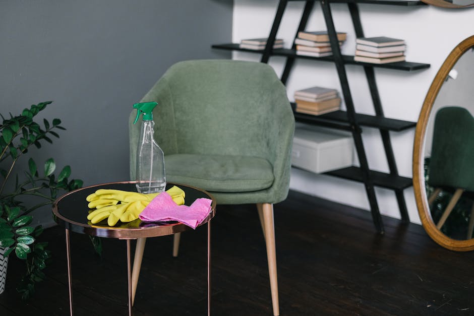 A flat lay arrangement of bathroom or spa accessories on a white marble surface, including a round woven placemat with a green soap bar and a pile of cotton swabs, a wooden brush with bristles, a white ceramic dispenser, and a lemon-colored towel. The scene features natural tones with beige, white, and green accents, illuminated by soft, natural lighting. A dried palm leaf lies nearby, adding a touch of organic texture. This image showcases elements related to personal hygiene and surface cleaning, reflecting the focus of domestic cleaning and sanitisation services offered by Cleaner Fulham, as referenced on the Parsons Green end of tenancy cleaning tips page.